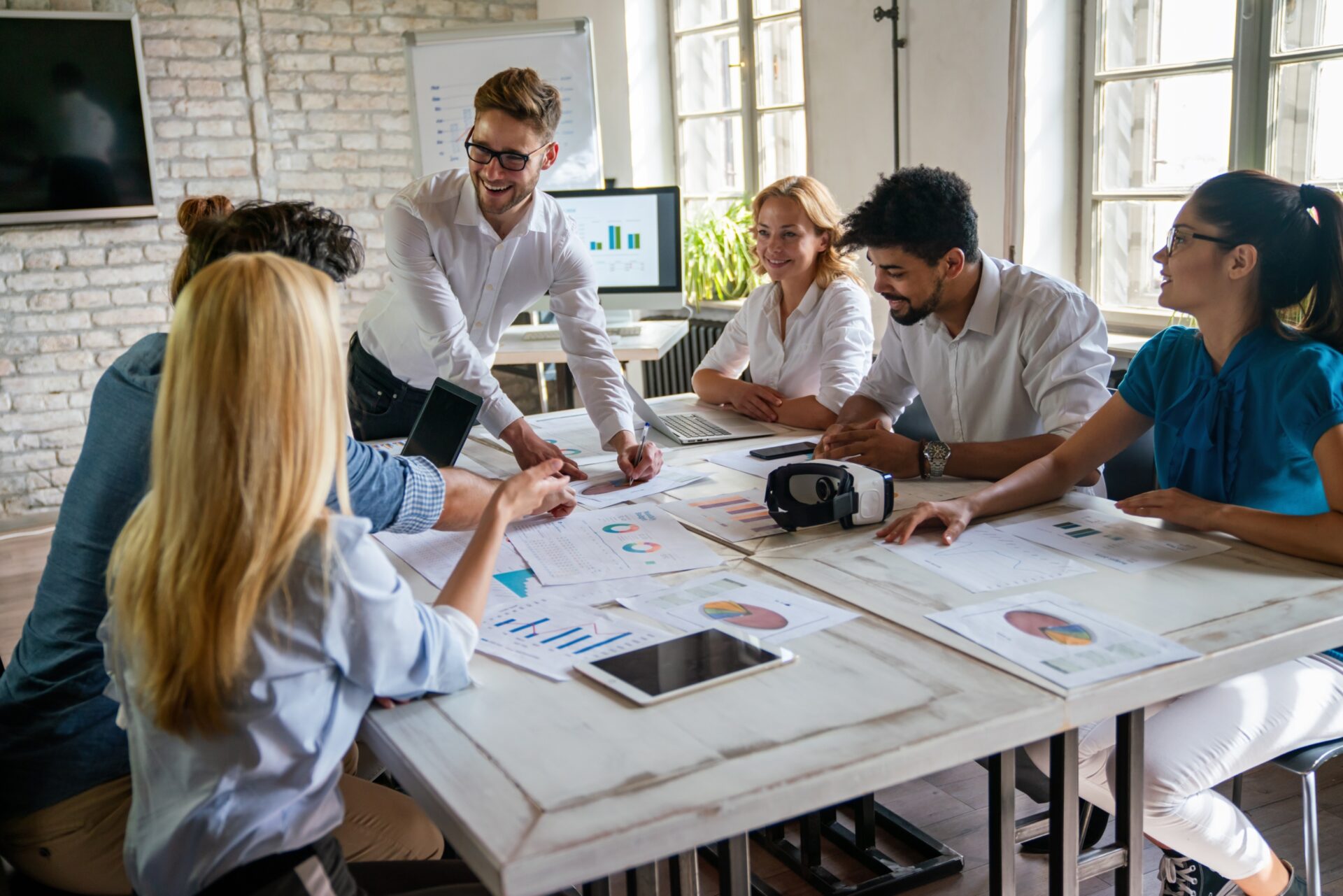 Smiling,Group,Of,Diverse,Businesspeople,Working,Together,Around,A,Meeting
